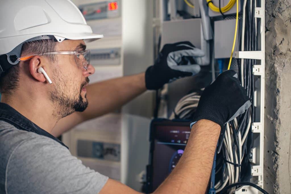 Man, an electrical technician working in a switchboard with fuses. Installation and connection of electrical equipment.